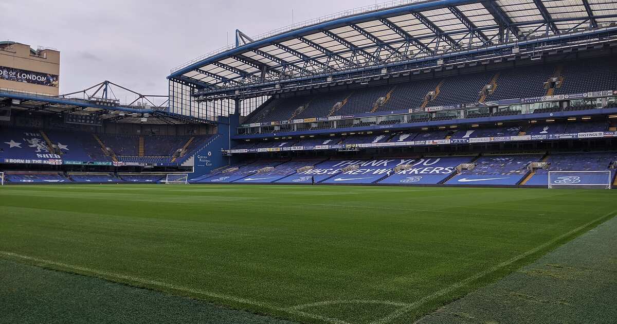 Looking across the pitch at Stamford Bridge from pitch level, with the blue stands and the roof of the main stand behind the goal line